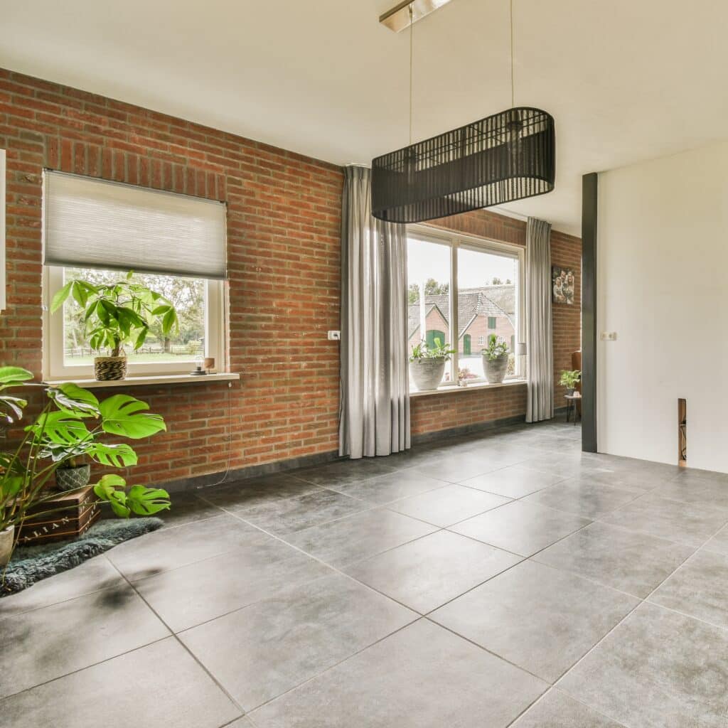 Mur brique rouge et carrelage gris : ambiance moderne Pièce vide au style industriel/moderne. Grand mur de briques rouges, sol carrelé gris foncé. Grande fenêtre et plafonnier noir design.
